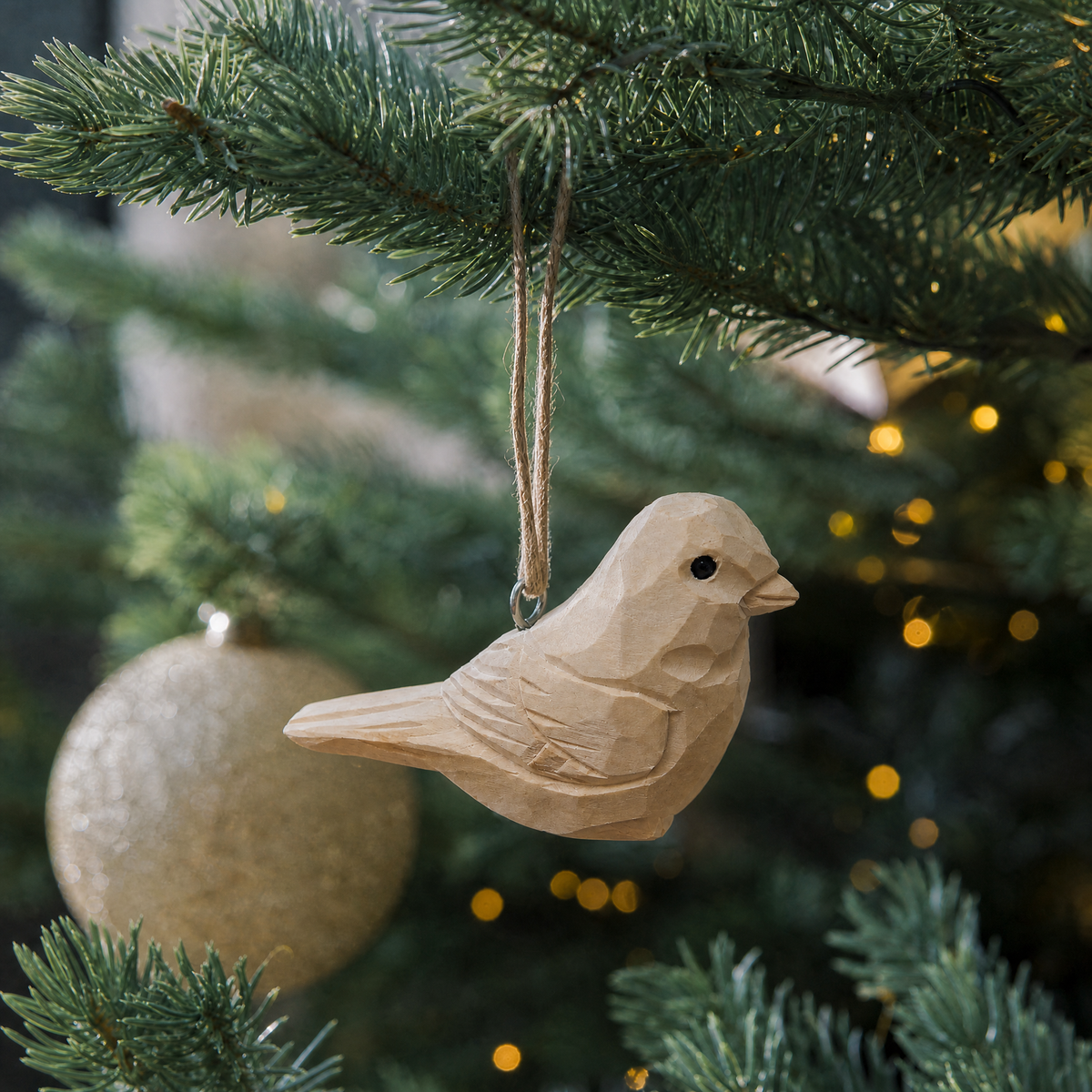 Unpainted Bird hand-carved wooden ornament by Selsela, hanging on a Christmas tree