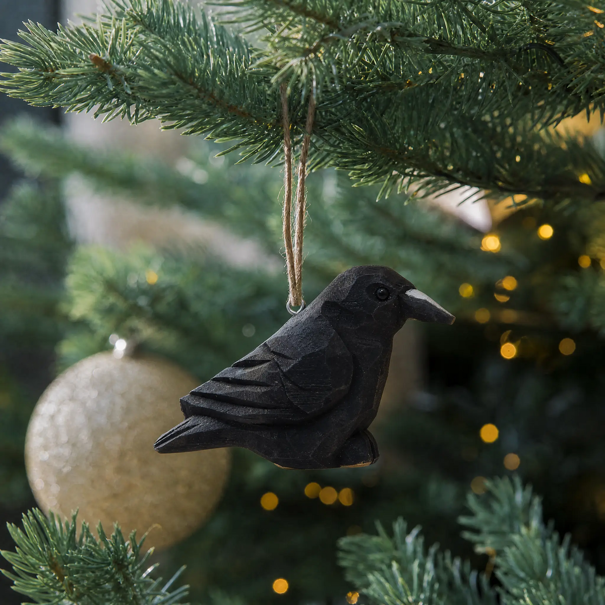 Raven hand-carved wooden ornament by Selsela, hanging on a Christmas tree