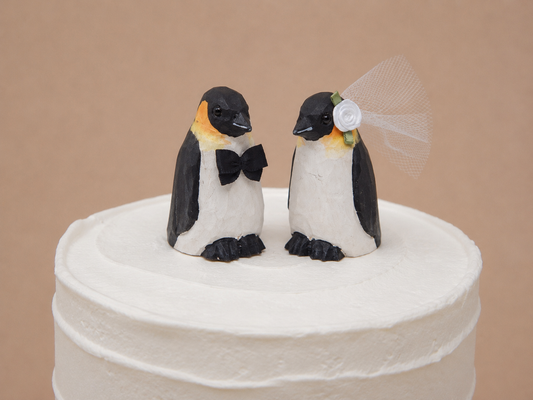 Penguin hand-carved wooden cake topper by Selsela, bride and groom pair on a wedding cake