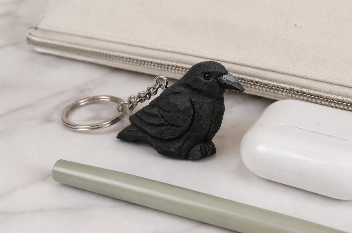 Raven hand-carved wooden keychain by Selsela, in a styled scene