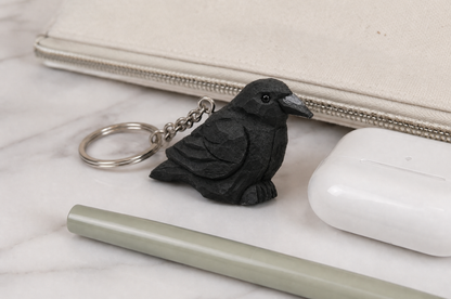 Raven hand-carved wooden keychain by Selsela, in a styled scene