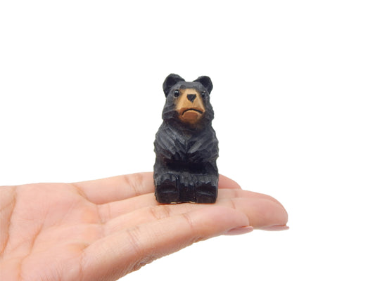 Black Bear hand-carved wooden figurine by Selsela, held in a hand for scale