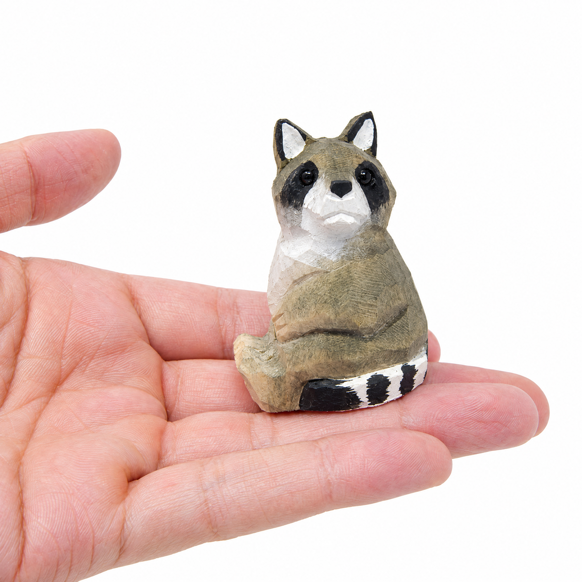Raccoon hand-carved wooden figurine by Selsela, on a plain background