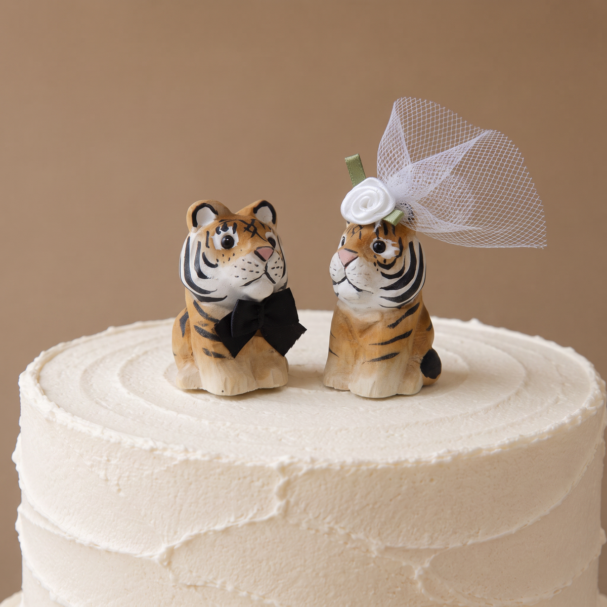 Tiger hand-carved wooden cake topper by Selsela, bride and groom pair on a wedding cake