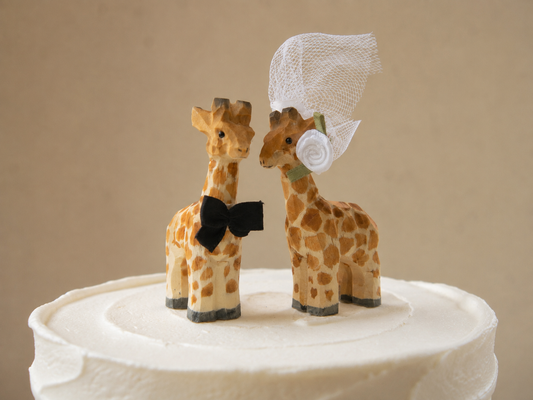 Giraffe hand-carved wooden cake topper by Selsela, bride and groom pair on a wedding cake