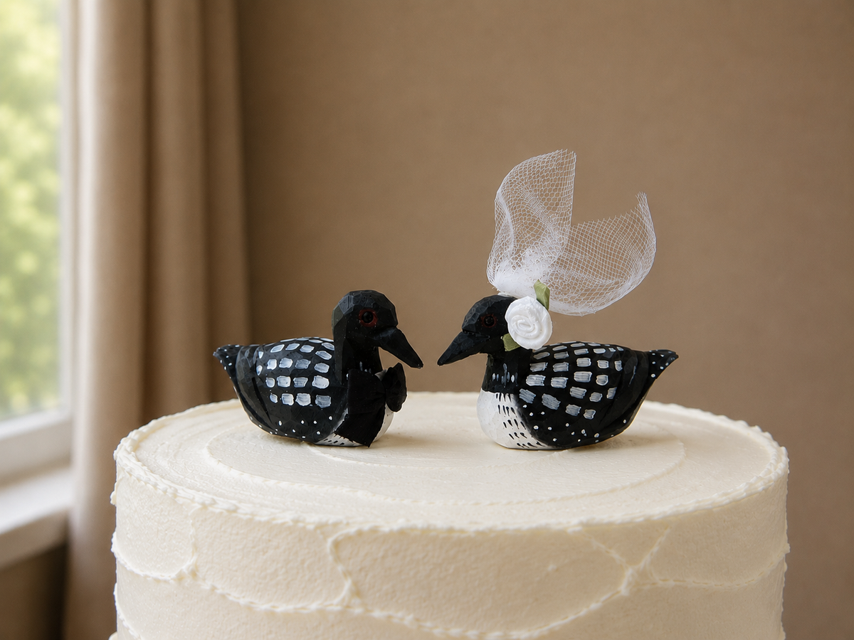Common Loon hand-carved wooden cake topper by Selsela, bride and groom pair on a wedding cake