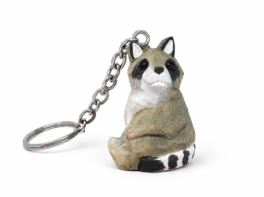 Raccoon hand-carved wooden keychain by Selsela, on a plain background