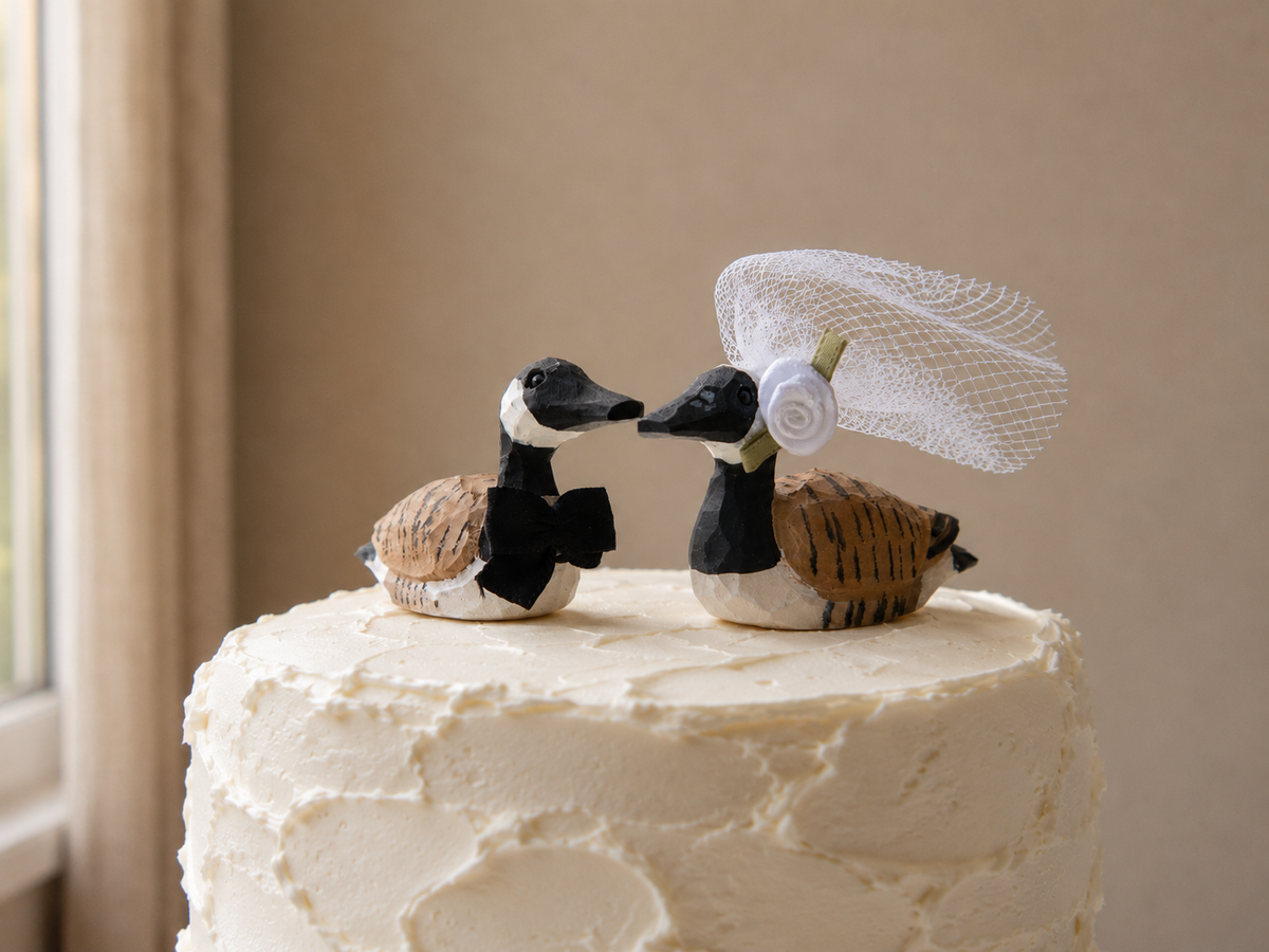 Canada Goose hand-carved wooden cake topper by Selsela, bride and groom pair on a wedding cake