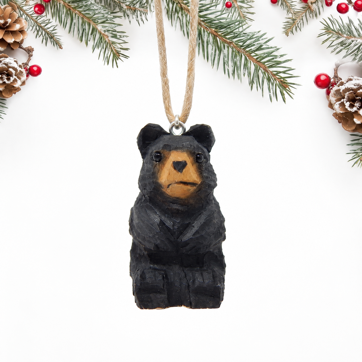 Black Bear hand-carved wooden ornament by Selsela, on a plain background