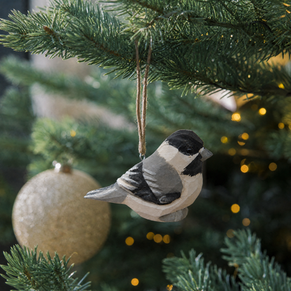 Chickadee hand-carved wooden ornament by Selsela, hanging on a Christmas tree