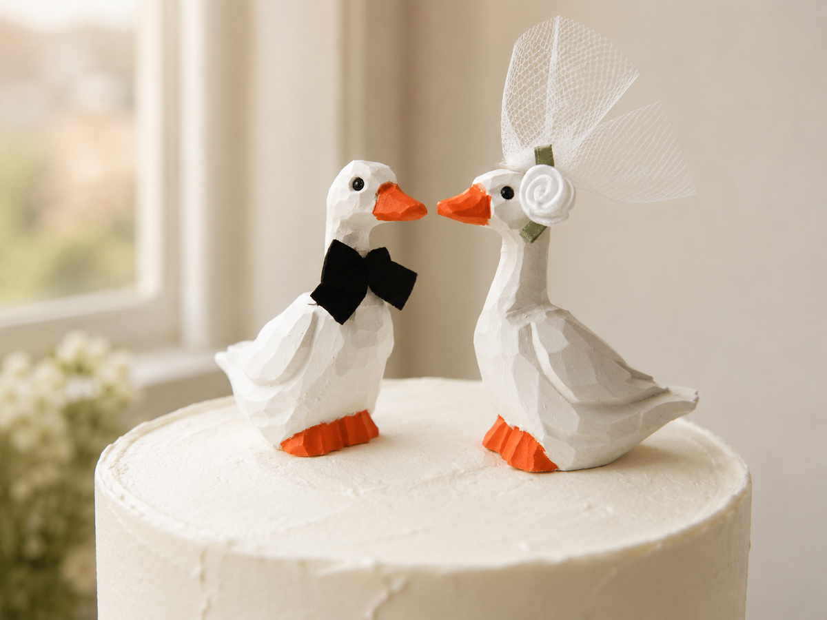 White Goose hand-carved wooden cake topper by Selsela, bride and groom pair on a wedding cake