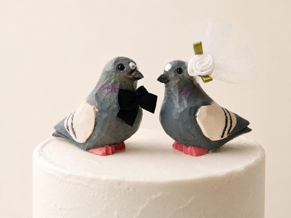 Pigeon hand-carved wooden cake topper by Selsela, bride and groom pair on a wedding cake