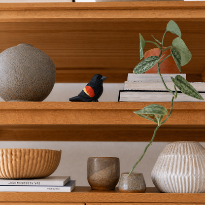 Red-Winged Blackbird hand-carved wooden figurine by Selsela, styled in a home setting