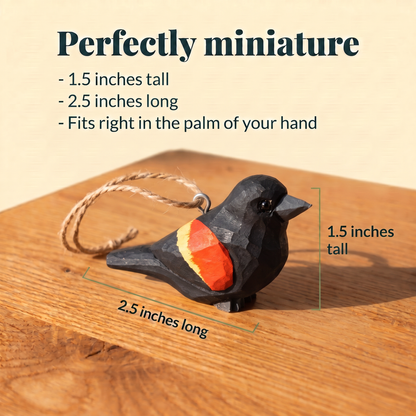 Wooden Red-Winged Blackbird ornament with a twine loop on a sunlit wood table, measured at 1.5 inches tall and 2.5 inches long. Text reads: Perfectly miniature, fits right in the palm of your hand.