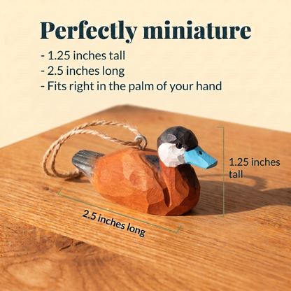Wooden Ruddy Duck ornament with a twine loop on a sunlit wood table, measured at 1.25 inches tall and 2.5 inches long. Text reads: Perfectly miniature, fits right in the palm of your hand.
